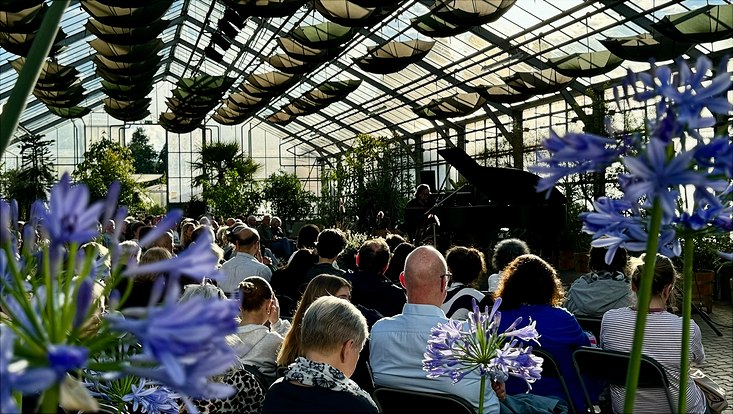 Thomas Lambrich im Gewächshaus des Loki-Schmidt-Gartens hinter seinem Flügel vor vollen Stuhlreihen