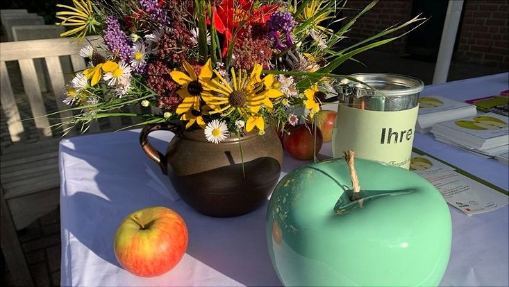 Tisch mit Blumenstrauß und Keramikäpfeln drauf