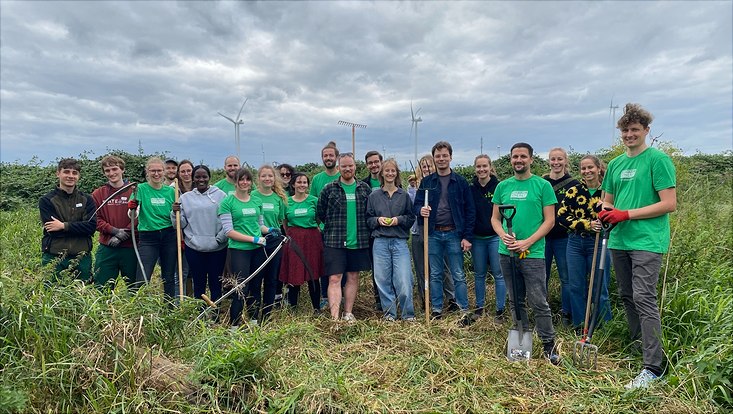 Ein großes Team freiwilliger Helfer der Loki Schmidt Stiftung mit Sensen in der Hand auf einer grünen Wiese